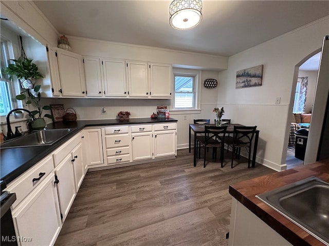 kitchen featuring white cabinets, ornamental molding, sink, and dark hardwood / wood-style flooring