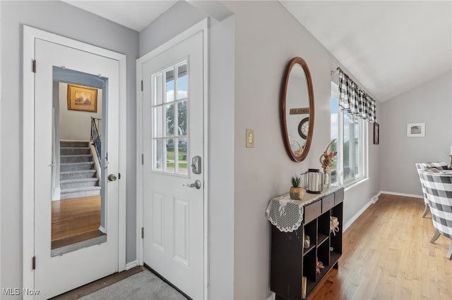 foyer with light wood-type flooring, vaulted ceiling, and a healthy amount of sunlight