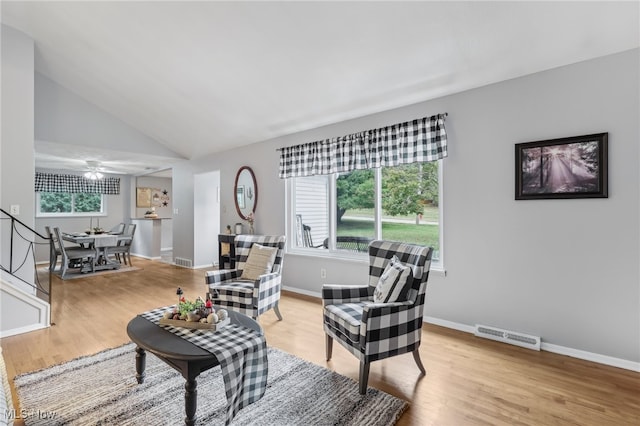 living room featuring light hardwood / wood-style flooring, ceiling fan, and high vaulted ceiling