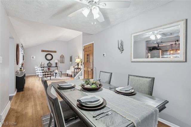 dining area with ceiling fan, a textured ceiling, lofted ceiling, and hardwood / wood-style floors