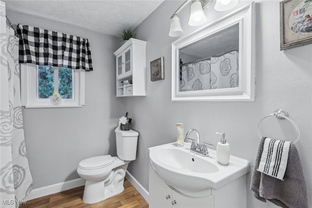 bathroom featuring a textured ceiling, wood-type flooring, vanity, and toilet