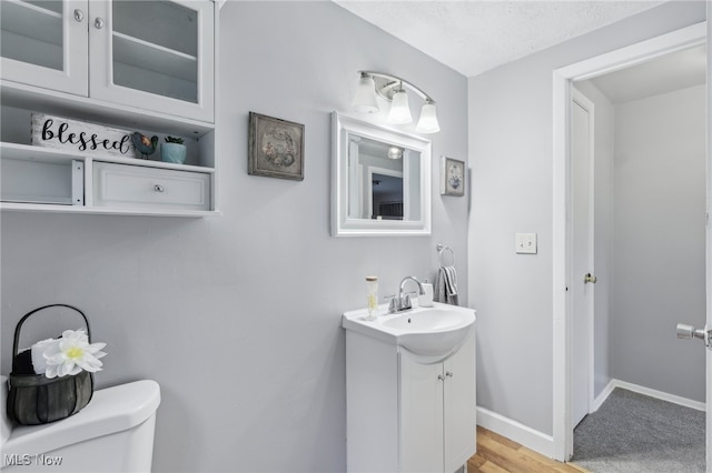 bathroom featuring a textured ceiling, hardwood / wood-style floors, vanity, and toilet