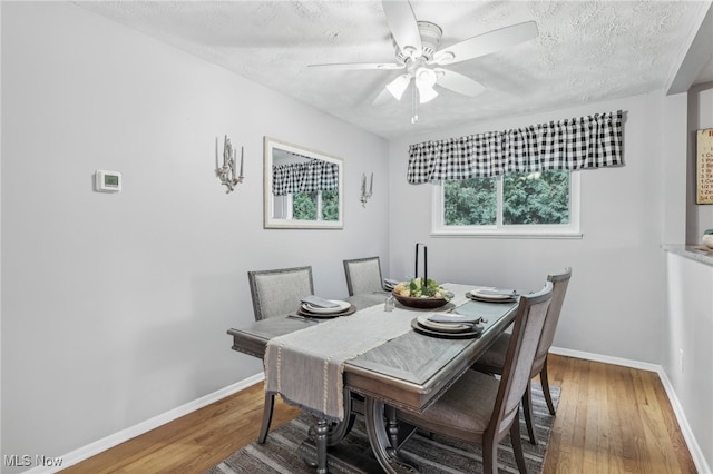 dining space featuring wood-type flooring, a textured ceiling, and ceiling fan