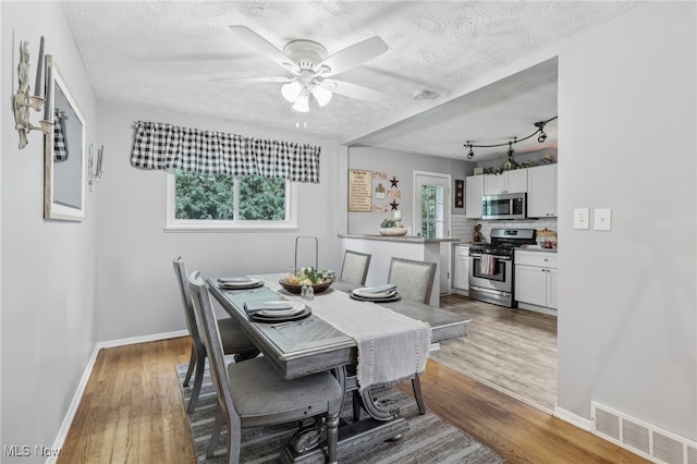 dining room featuring a textured ceiling, hardwood / wood-style floors, and ceiling fan