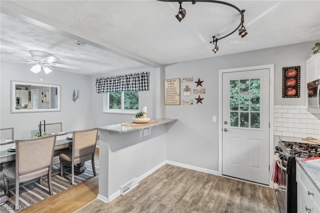 kitchen featuring a textured ceiling, light hardwood / wood-style floors, stainless steel appliances, and white cabinets