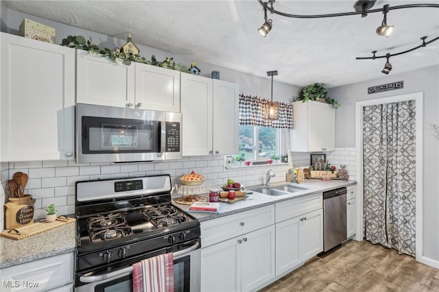 kitchen featuring light hardwood / wood-style floors, sink, white cabinetry, decorative backsplash, and appliances with stainless steel finishes