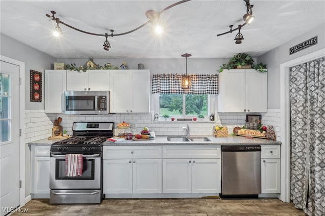 kitchen featuring appliances with stainless steel finishes, backsplash, sink, and white cabinets