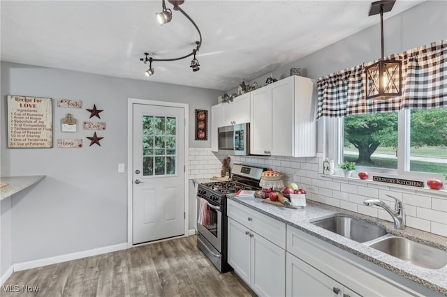 kitchen featuring tasteful backsplash, sink, white cabinets, appliances with stainless steel finishes, and hardwood / wood-style floors