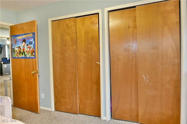 unfurnished bedroom featuring light carpet and multiple closets