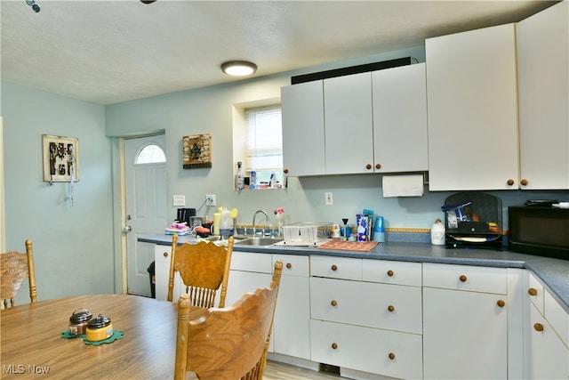 kitchen with white cabinets, light wood-type flooring, and sink