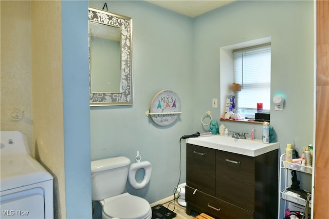 bathroom with wood-type flooring, vanity, toilet, and washer / dryer