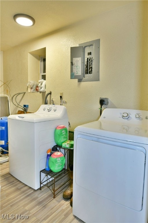 laundry room with light hardwood / wood-style floors, electric panel, and washer and dryer