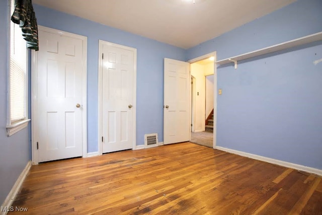 unfurnished bedroom featuring two closets and hardwood / wood-style floors