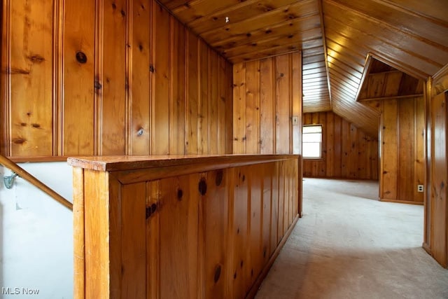 hallway featuring light carpet, wood walls, vaulted ceiling, and wooden ceiling