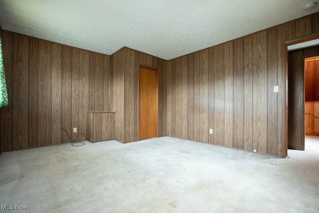 carpeted spare room featuring wooden walls