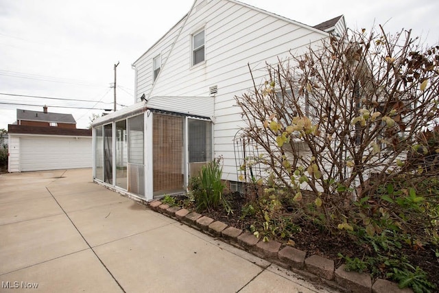 view of side of home with a sunroom and a patio area