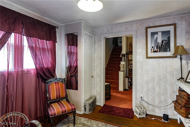 living area featuring wood-type flooring, a textured ceiling, and crown molding