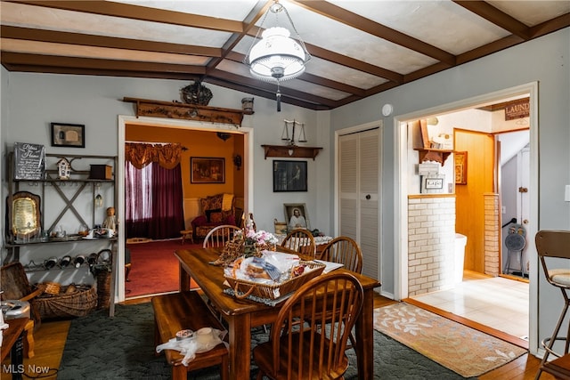 dining room featuring wood-type flooring and lofted ceiling with beams