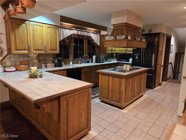 kitchen featuring sink, black appliances, kitchen peninsula, and tile counters