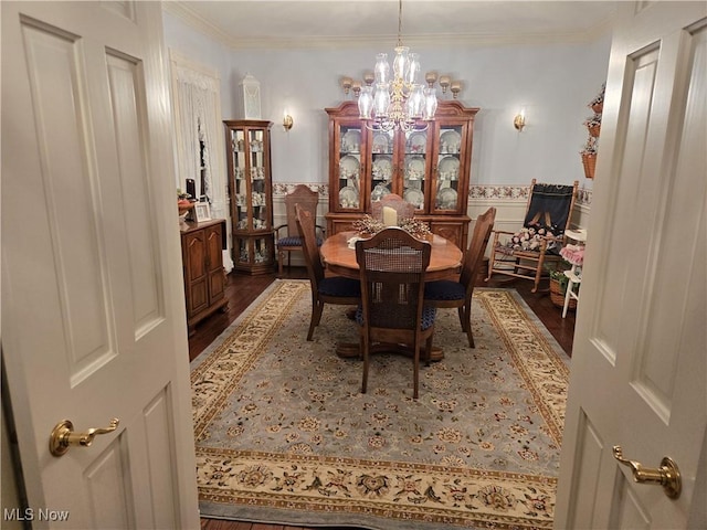 dining space with dark wood-type flooring, an inviting chandelier, and crown molding