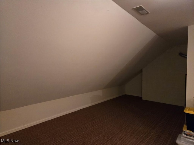 bonus room with lofted ceiling and dark colored carpet