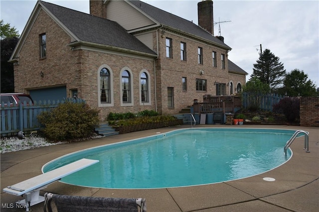 view of swimming pool with a diving board