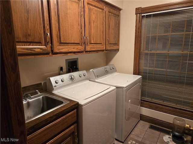 laundry room with sink, washing machine and dryer, light tile patterned flooring, and cabinets