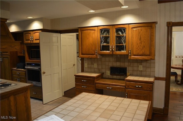 kitchen featuring tile countertops, stainless steel oven, and tasteful backsplash