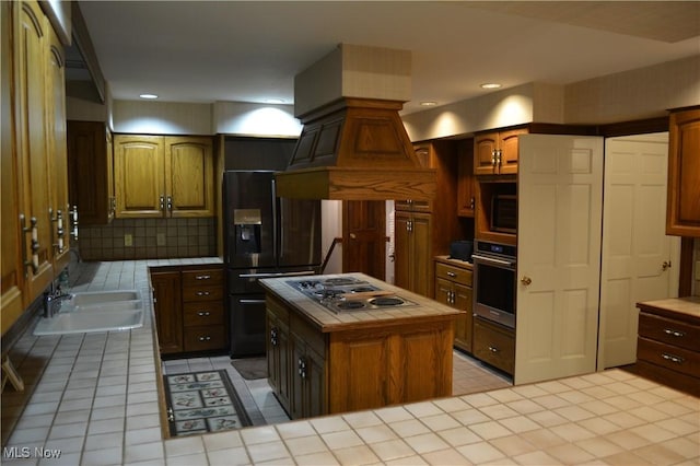 kitchen with tile counters, stainless steel appliances, decorative backsplash, a kitchen island, and sink