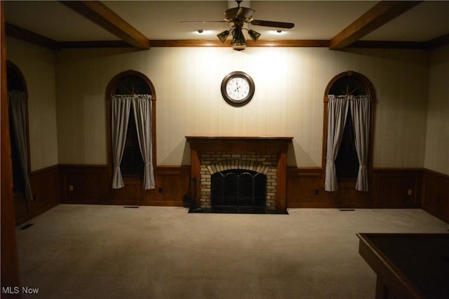 carpeted living room with a fireplace, ceiling fan, and beamed ceiling