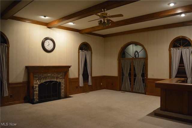 carpeted living room with a brick fireplace, ceiling fan, and beamed ceiling