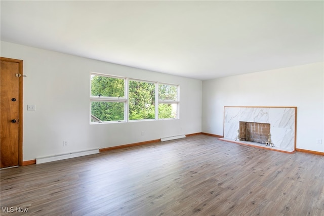 unfurnished living room with a baseboard heating unit, a high end fireplace, and wood-type flooring