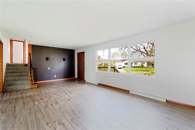 unfurnished living room featuring light wood-type flooring and a baseboard heating unit