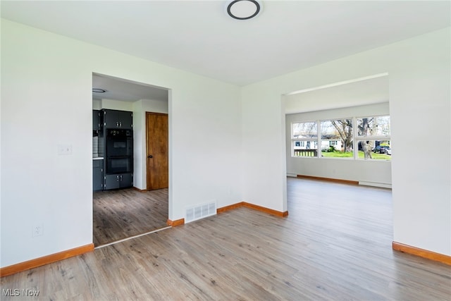 spare room with hardwood / wood-style flooring and a baseboard radiator