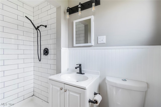 bathroom with a tile shower, vanity, and toilet