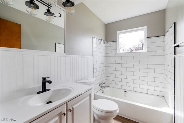 full bathroom featuring hardwood / wood-style floors, vanity, tiled shower / bath combo, and toilet