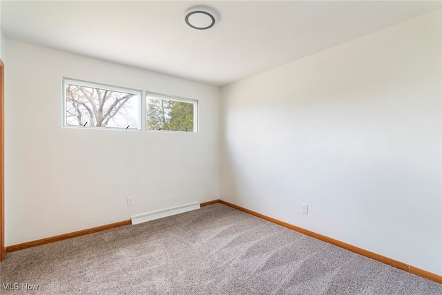 carpeted spare room featuring a baseboard heating unit