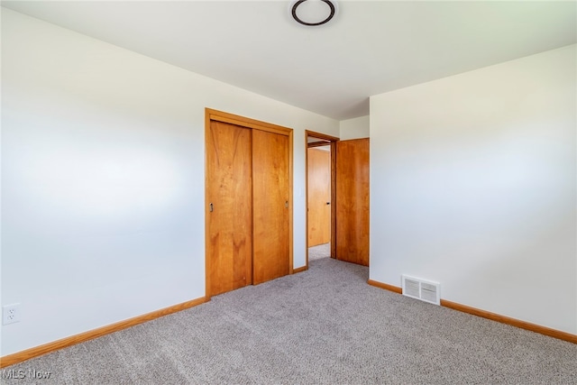 unfurnished bedroom featuring light carpet and a closet