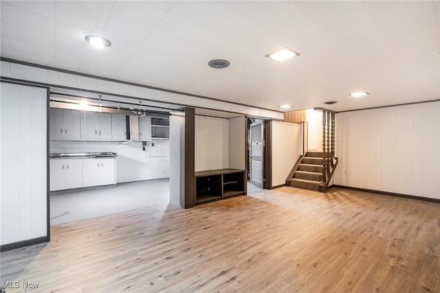 basement featuring light hardwood / wood-style floors and wooden walls