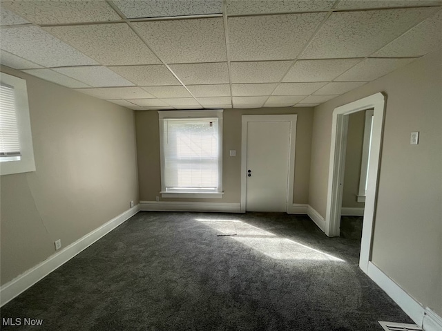 carpeted spare room featuring a drop ceiling