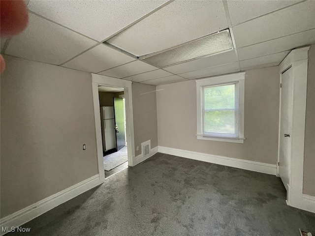 unfurnished room featuring a paneled ceiling and dark colored carpet