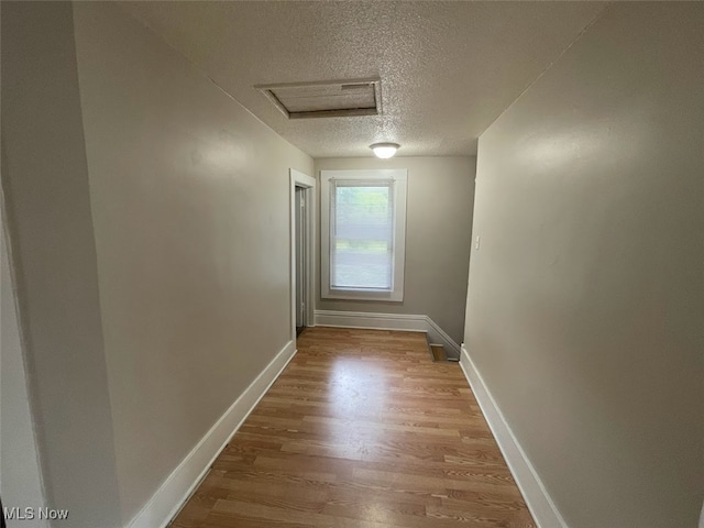 hall with a textured ceiling and hardwood / wood-style flooring