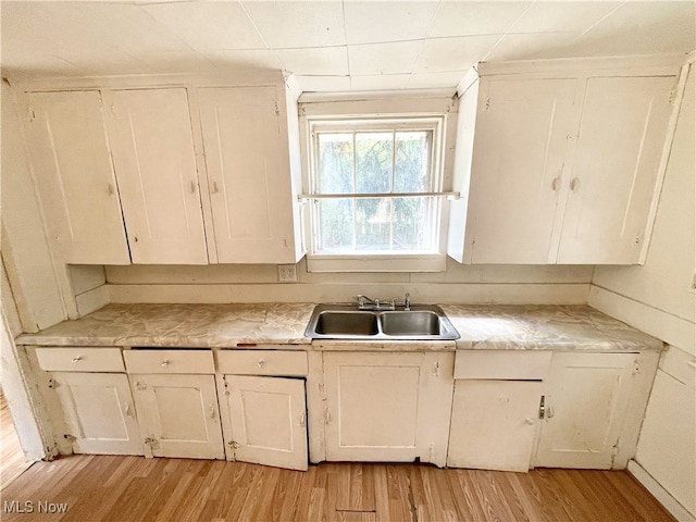 kitchen with light hardwood / wood-style floors, sink, and white cabinetry