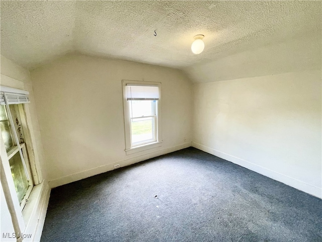 bonus room featuring dark carpet, a textured ceiling, and lofted ceiling