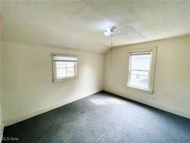 carpeted empty room featuring a textured ceiling and vaulted ceiling