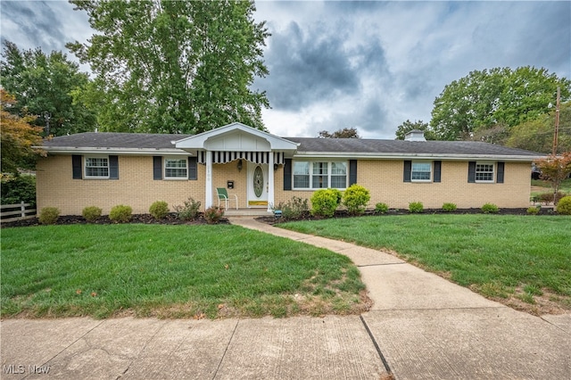 single story home featuring a chimney, fence, a front lawn, and brick siding