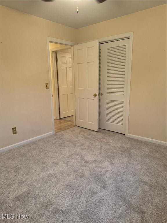 unfurnished bedroom with a closet and light colored carpet