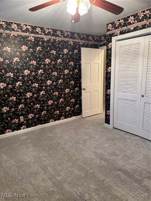 unfurnished bedroom featuring carpet flooring, a closet, and ceiling fan