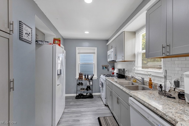 kitchen featuring decorative backsplash, gray cabinetry, white appliances, sink, and light hardwood / wood-style flooring