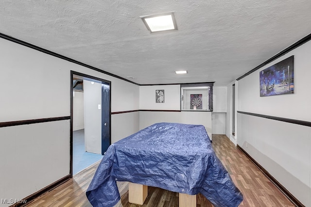 bedroom featuring hardwood / wood-style flooring, crown molding, and a textured ceiling